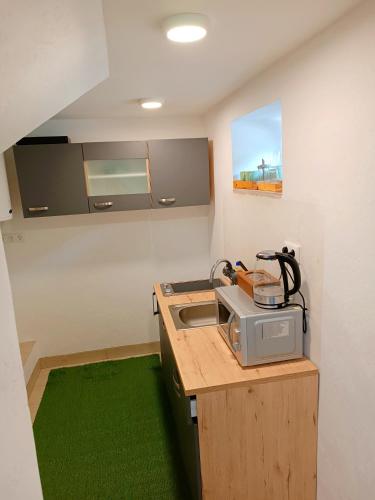 a kitchen with a microwave on a counter with green carpet at Apartments Romantic and Family Room Zemlinski in Payerbach