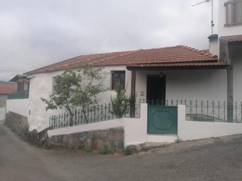 a white house with a green door and a fence at Villa Cantinho dos Avós in Baião