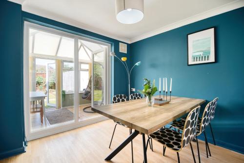a dining room with blue walls and a wooden table and chairs at Beautiful Aldeburgh Coastal Getaway in Aldeburgh