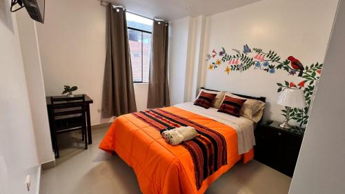 a bedroom with a bed with an orange blanket and a window at Miranda's House in Puerto Chicama