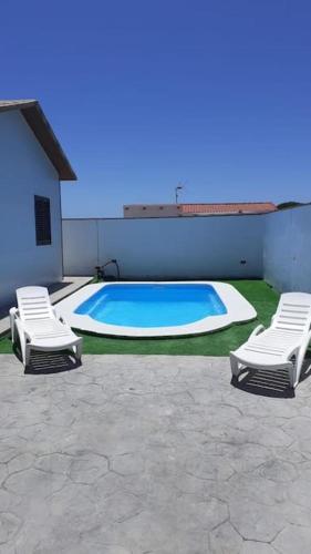 two chairs and a swimming pool next to a building at Casa Alejandra en el palmar in Cádiz