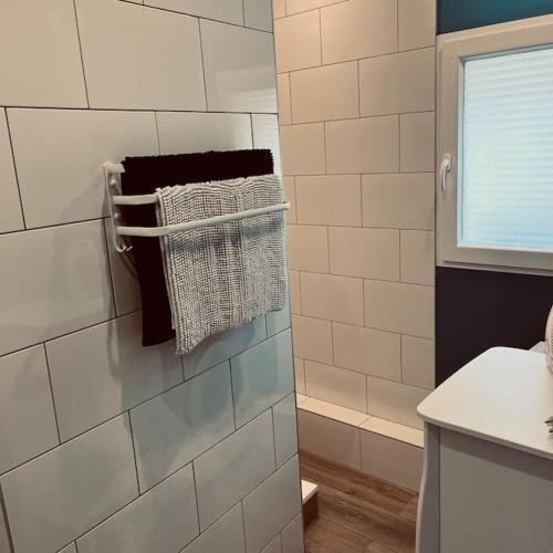 - une salle de bains carrelée de blanc avec un porte-serviettes sur le mur dans l'établissement Appartement tout confort climatisé, à Saint-Uze