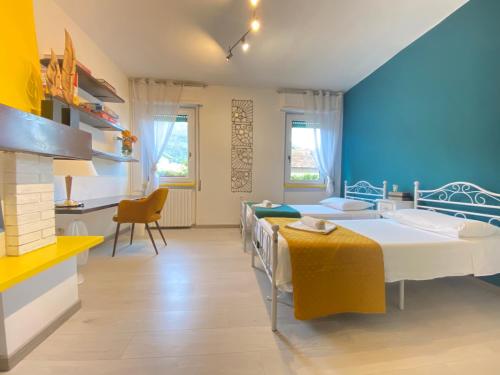a bedroom with two beds and a desk and a kitchen at CLUA Holiday House in Porto Ceresio