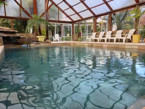 a swimming pool with chairs and a glass roof at Apartamentos PREMIUM CON YACUZZI DUNAS DEL ESTE in Punta Colorada