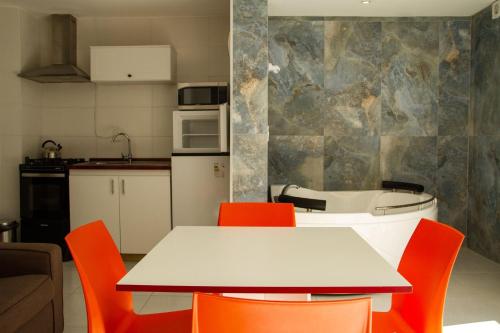 a kitchen with a table and orange chairs at Apartamentos PREMIUM CON YACUZZI DUNAS DEL ESTE in Punta Colorada