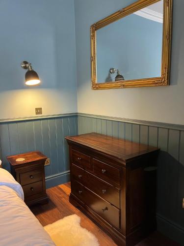 a bedroom with a dresser and a mirror on the wall at Lewis Lodge - Stunning & Exclusive Luxury Home in the Heart of Ballater, Royal Deeside in Ballater