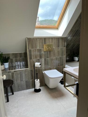 a bathroom with a toilet and a sink and a skylight at Lewis Lodge - Stunning & Exclusive Luxury Home in the Heart of Ballater, Royal Deeside in Ballater