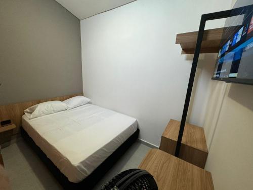 a small bedroom with a bed and a television at Hotel La Fábrica cerca al aeropuerto in Palmira