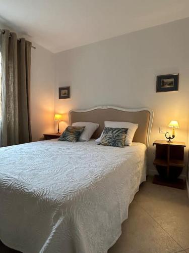 une chambre avec un lit blanc avec deux oreillers dans l'établissement T3 avec jardin proche plage et ville, à Cavalaire-sur-Mer