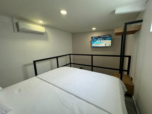 a bedroom with a bed with a tv on the wall at Hotel La Fábrica cerca al aeropuerto in Palmira