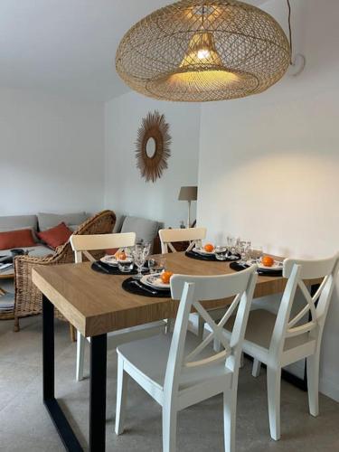 une table à manger avec des chaises blanches et un lustre dans l'établissement T3 avec jardin proche plage et ville, à Cavalaire-sur-Mer