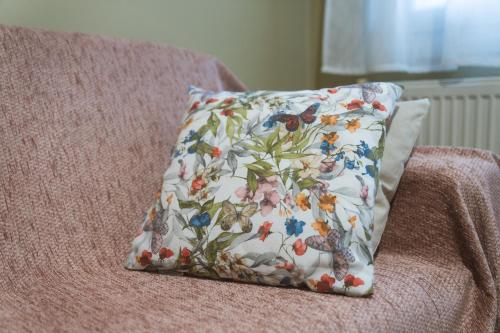 a pillow sitting on a couch with a flower pattern at Roots House Pozar in Piperiaí