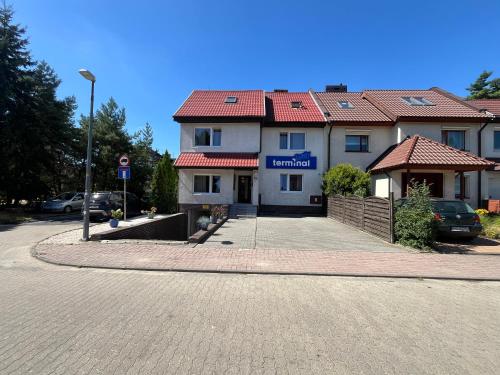 a building with a red roof on a street at Terminal Family Airport in Poznań