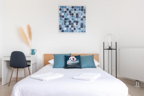 une chambre avec un lit blanc avec des oreillers bleus dans l'établissement L'ensoleillé Superbe studio avec garage, à Caen