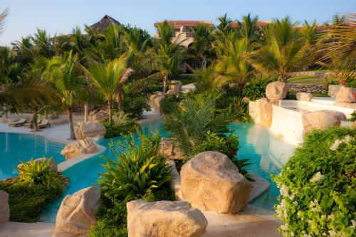 an image of a resort pool with rocks and palm trees at Swahili Beach in Diani Beach
