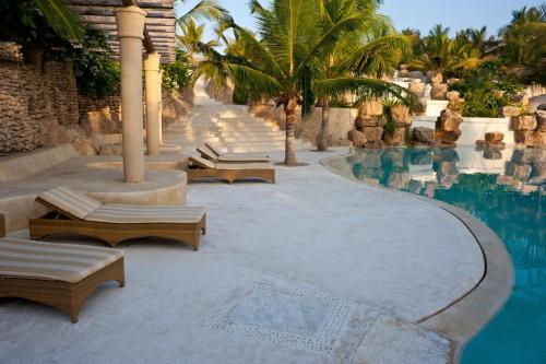 a swimming pool with chaise lounge chairs next to a resort at Swahili Beach in Diani Beach
