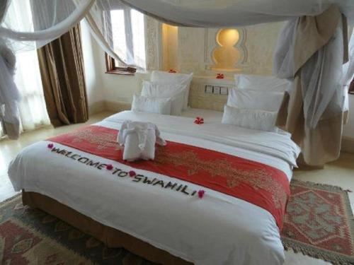 a bedroom with a large bed with a stuffed animal on it at Swahili Beach in Diani Beach