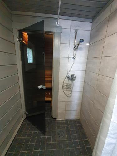 a shower with a glass door in a bathroom at Pieni Katajaranta in Karvonen
