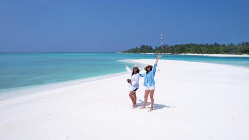two people on a beach with their arms in the air at La Palma Suites in Ukulhas