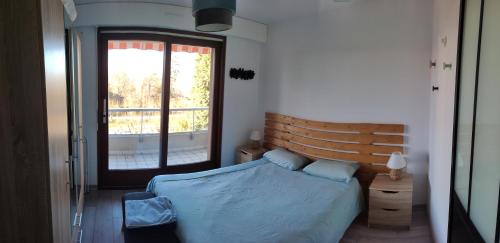 une chambre avec un lit avec une tête de lit en bois et une fenêtre dans l'établissement Entre lac et montagnes, à Thonon-les-Bains