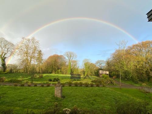 a rainbow in the sky over a green field at Les Gîtes du Manoir de Keryvon in Saint-Derrien