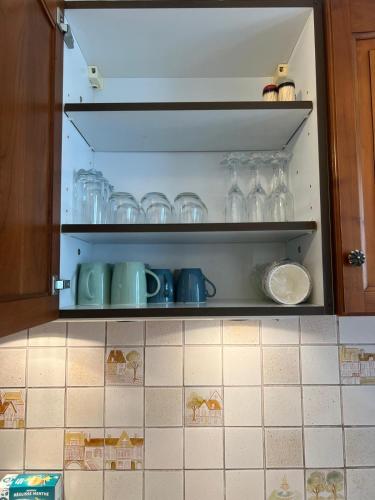 a cupboard filled with glasses and plates in a kitchen at Champion suites in Sarcelles