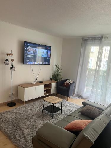 a living room with a couch and a tv on the wall at Champion suites in Sarcelles