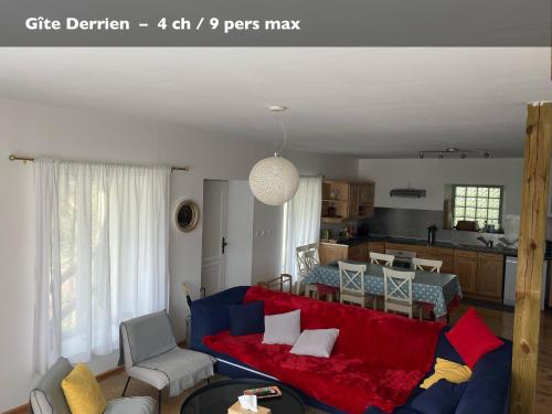 a living room with a red couch and a kitchen at Les Gîtes du Manoir de Keryvon in Saint-Derrien