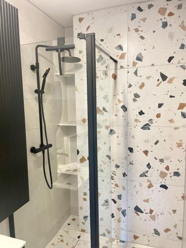 a shower in a bathroom with a wall covered in rocks at Szmaragdowa Sowa in Wałbrzych