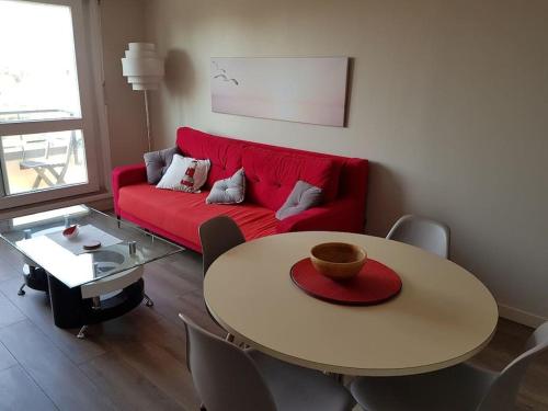 a living room with a red couch and a table at LE PATIO -PLAGE vue mer ,Normandie,Juno Beach in Courseulles-sur-Mer