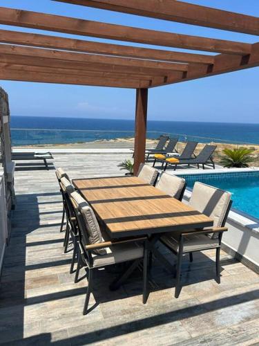 a wooden table and chairs on a deck with a pool at Penthouse med privat saltvannsbasseng på Esentepe Beach in Kérynia