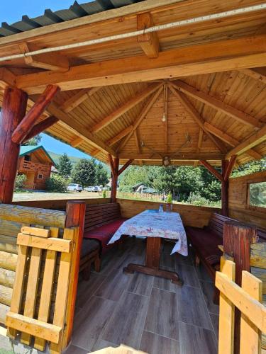 a wooden pavilion with a table and chairs on a deck at Konaci Očeva Zemlja Vikendica i Bungalovi in Mojkovac