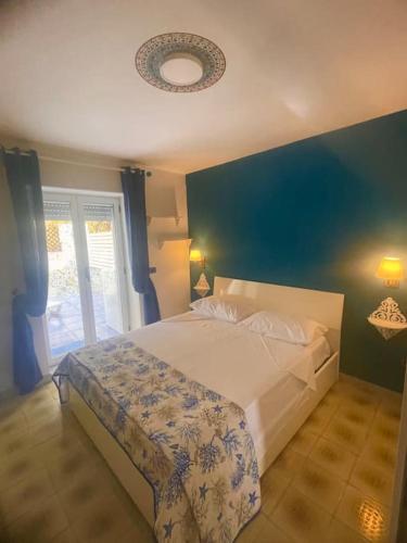 una camera da letto con un letto grande con una parete blu di La casa sul blu Acciaroli Casa Vacanze ad Acciaroli