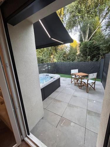 une terrasse arrière avec un bain à remous et une table dans l'établissement La suite secrète et son spa abrité, à Nancy