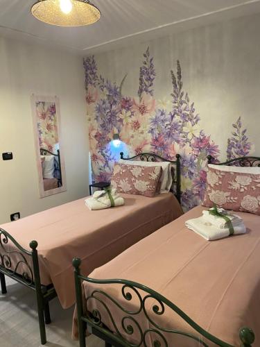 a bedroom with two beds and a floral wall at Palazzo Carignano in Chioggia