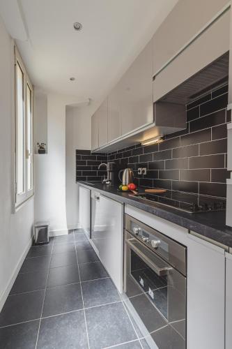 une cuisine avec des appareils en acier inoxydable et du carrelage noir dans l'établissement Bohème-Chic au cœur du VIEUX NICE #Lovely, à Nice