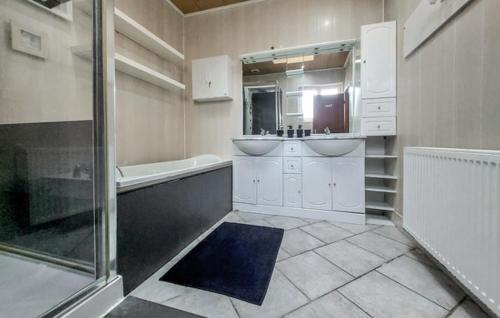 une salle de bain avec deux lavabos, une baignoire et un miroir dans l'établissement Grand gîte chez Gina, à Grand-Fort-Philippe