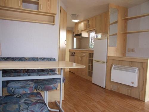 une petite cuisine avec une table et un réfrigérateur dans l'établissement mobil home en pleine nature avec piscine proche, à Escaro
