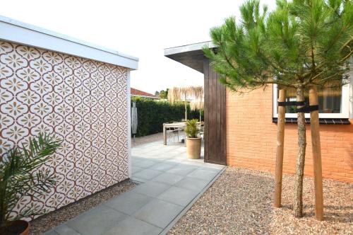 a house with a courtyard with a palm tree at Casita Ouddorp aan Zee in Ouddorp