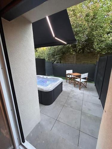 une terrasse avec un bain à remous, une table et des chaises dans l'établissement La terrasse abritée et son spa, à Nancy