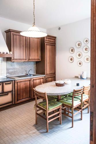 a kitchen with wooden cabinets and a table and chairs at Casa Vacanze - SportHoliday House Segusino-Valdobbiadene in Segusino