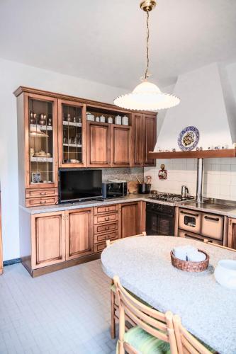 a kitchen with wooden cabinets and a round table at Casa Vacanze - SportHoliday House Segusino-Valdobbiadene in Segusino