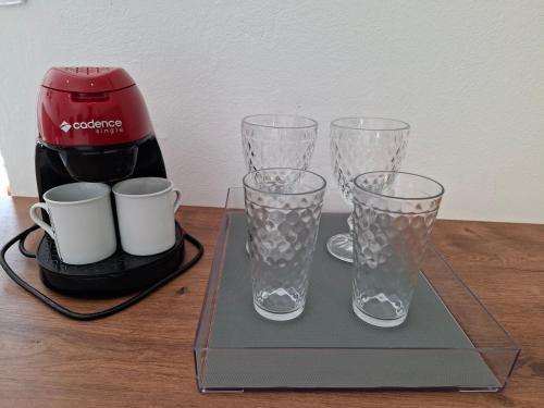 three glasses sitting on a tray next to a coffee maker at Embahu Suítes - Vista para Pedra do Baú e banheira de imersão in Santo Antônio do Pinhal