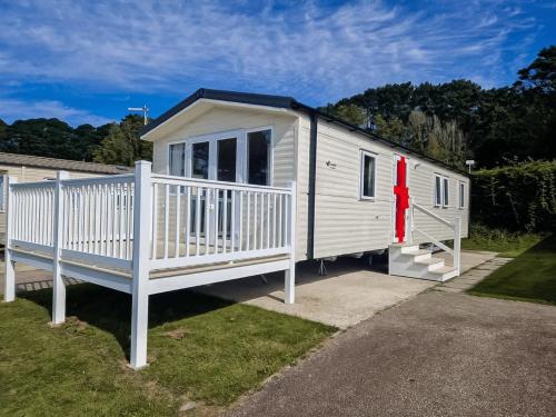 a white tiny house with a porch and a red ribbon at Dog Friendly 8 Berth Static Caravan Newquay in Newquay