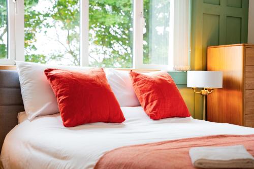 a bed with two red pillows on top of it at The Brambles Retreat in the Mournes in Annalong