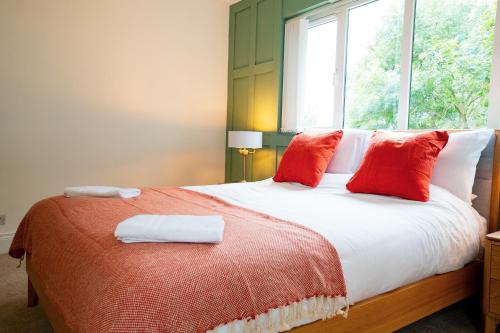 a bedroom with a bed with red pillows and a window at The Brambles Retreat in the Mournes in Annalong