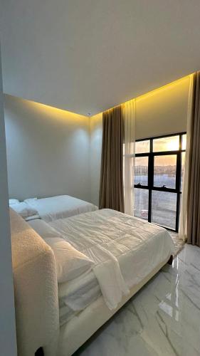 a white bedroom with a large bed and a window at Dirat Al-Ghizal 1 راس الخيمة قرية اذن in Gragrah