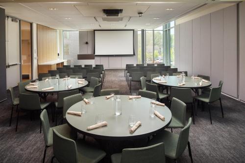 a conference room with tables and chairs and a screen at The Heartwood in Poughkeepsie