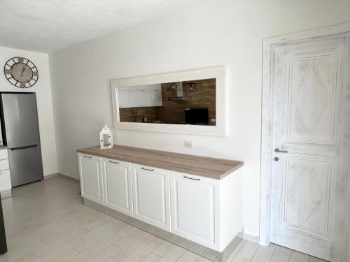 a kitchen with white cabinets and a mirror on the wall at splendido appartamento con piscina a due passi dalla spiaggia in Palau