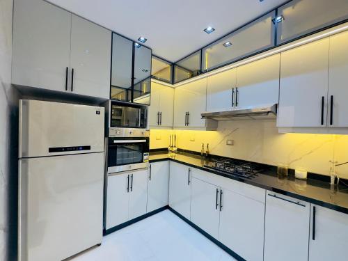 a large white kitchen with white cabinets and appliances at Heart of Al Mohandiseen in Cairo